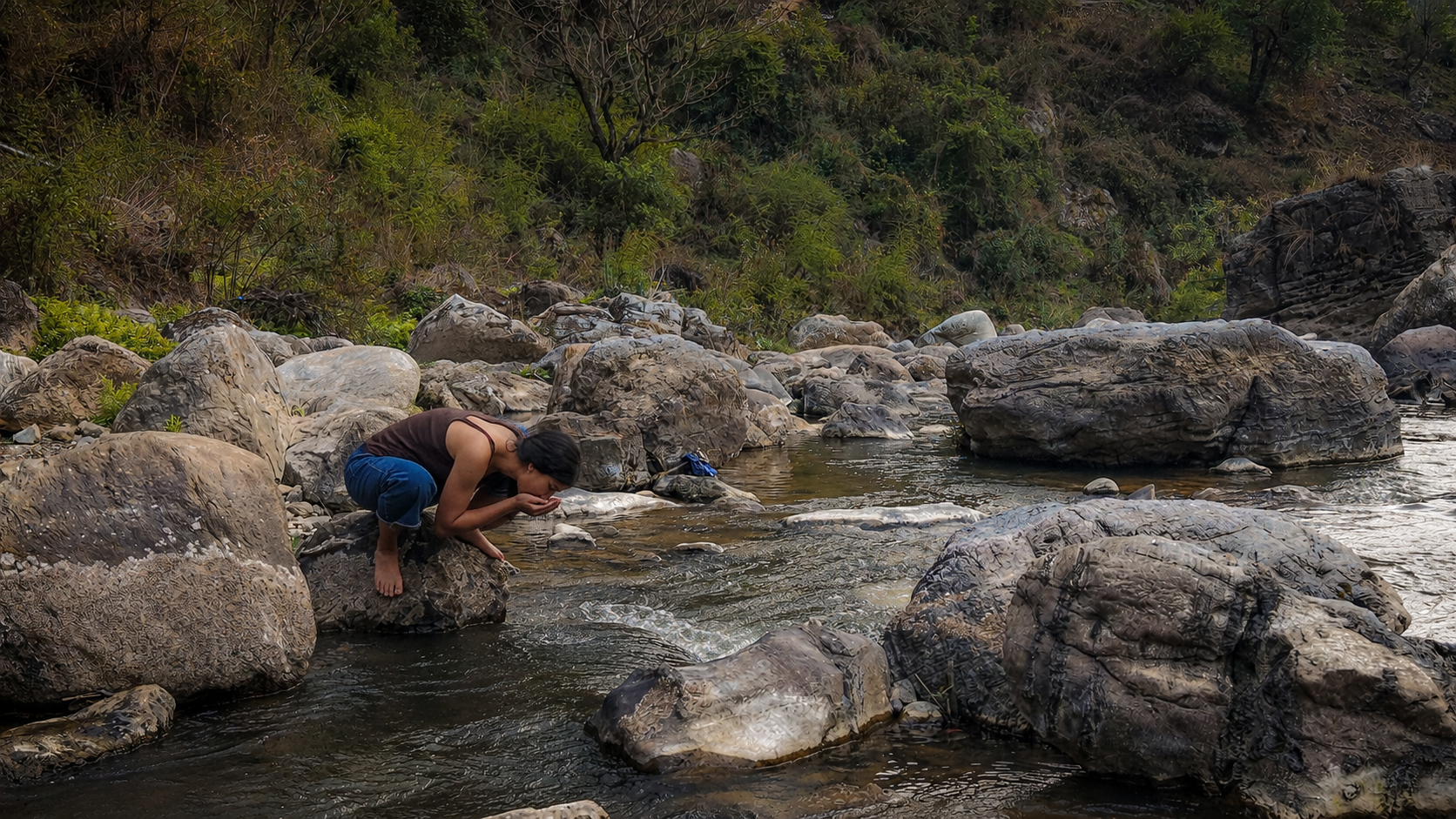 Person drinking from a clean mountain stream